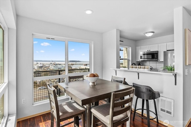 dining room featuring dark wood-style floors, visible vents, plenty of natural light, and baseboards