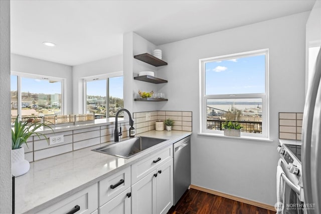 kitchen with dark wood-style flooring, open shelves, stainless steel appliances, a sink, and baseboards