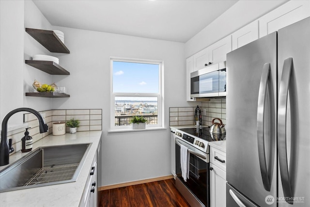 kitchen with stainless steel appliances, backsplash, dark wood-type flooring, white cabinets, and a sink