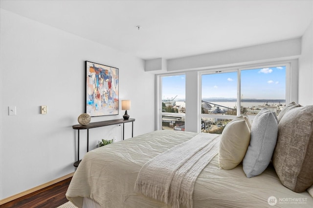 bedroom featuring a water view and wood finished floors