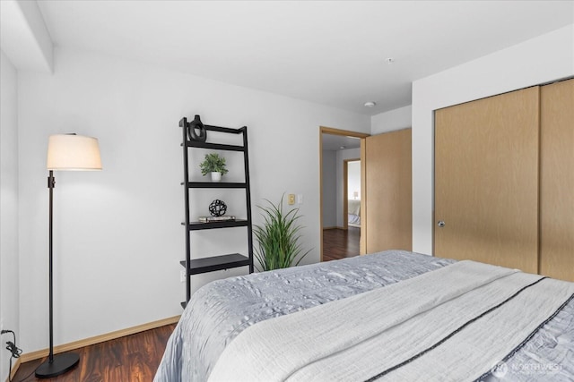 bedroom featuring dark wood-type flooring, a closet, and baseboards