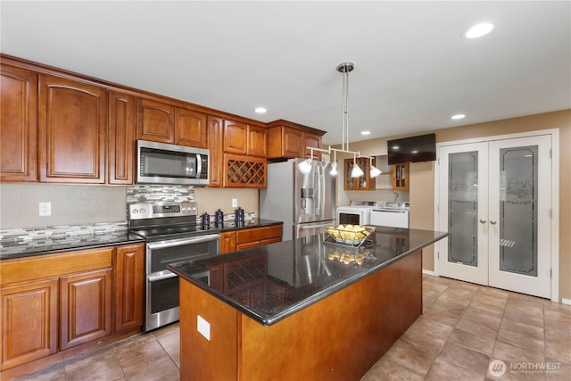 kitchen with stainless steel appliances, brown cabinetry, washing machine and dryer, and a center island