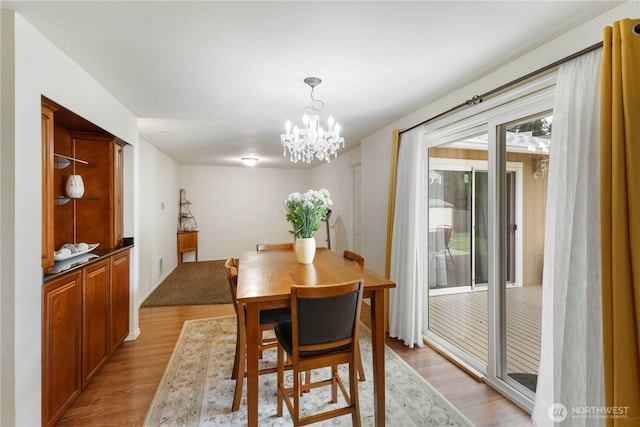 dining area with light wood-type flooring and an inviting chandelier