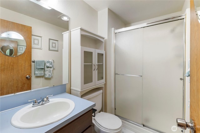 full bathroom featuring toilet, a stall shower, and vanity