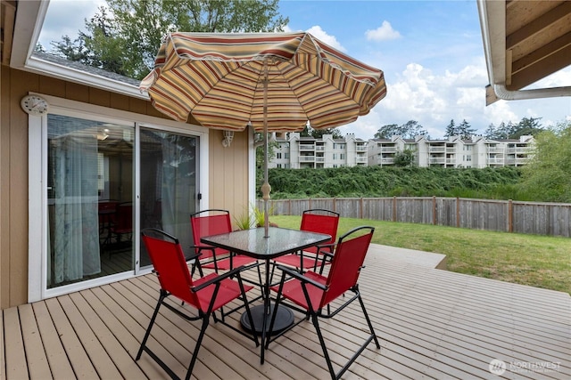 wooden deck with fence, outdoor dining area, and a lawn