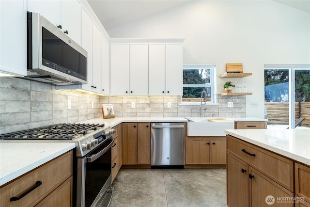 kitchen featuring tasteful backsplash, vaulted ceiling, stainless steel appliances, white cabinetry, and a sink