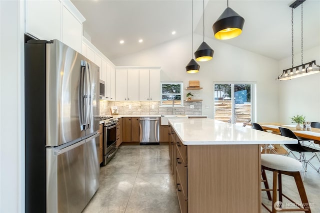 kitchen featuring stainless steel appliances, a kitchen island, finished concrete flooring, light countertops, and a kitchen bar