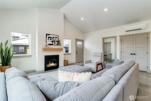 living area featuring plenty of natural light, high vaulted ceiling, a glass covered fireplace, and a wall mounted AC