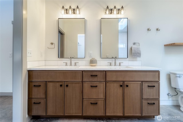 full bath with a sink, toilet, and double vanity