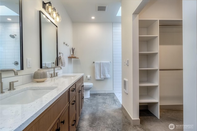 full bath with toilet, double vanity, a sink, and visible vents