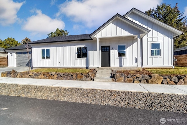 modern inspired farmhouse featuring a garage, driveway, board and batten siding, and roof with shingles