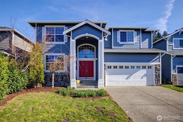 traditional-style house featuring concrete driveway, stone siding, and an attached garage