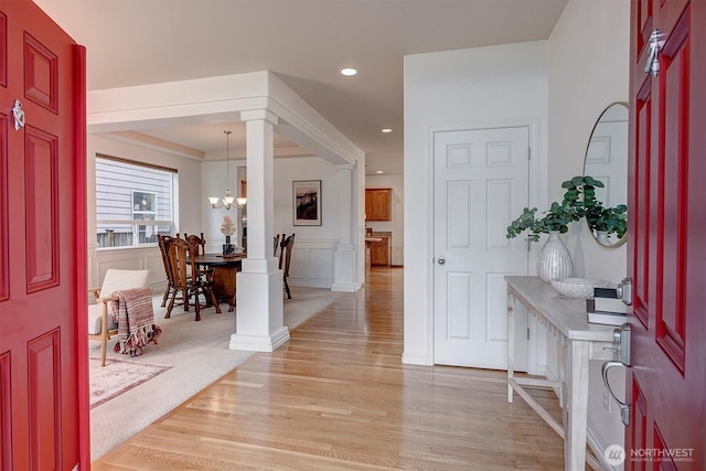 entryway with a decorative wall, light wood-type flooring, recessed lighting, and a notable chandelier