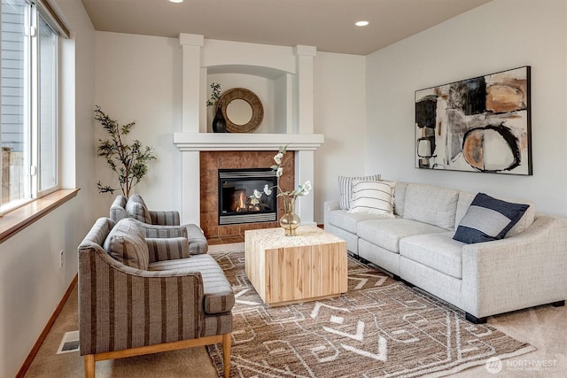 living room with carpet, visible vents, a wealth of natural light, and a tile fireplace