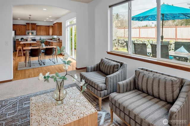 living room with arched walkways, light wood-style flooring, baseboards, and recessed lighting