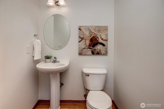 half bath featuring a sink, toilet, and baseboards