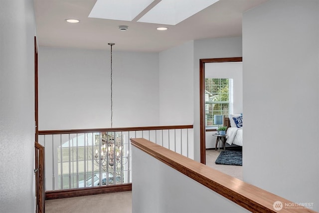 corridor with carpet floors, a skylight, an inviting chandelier, and recessed lighting