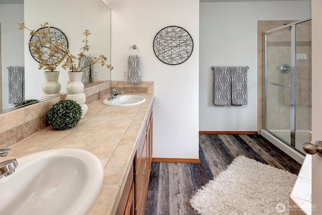 full bathroom featuring a sink, a shower stall, baseboards, and wood finished floors