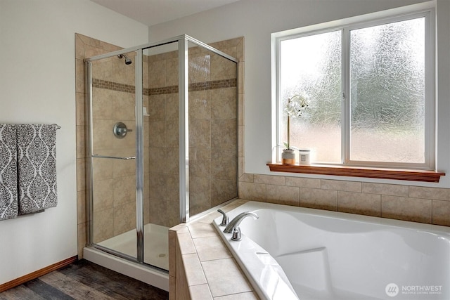 full bath featuring a shower stall, baseboards, a bath, and wood finished floors