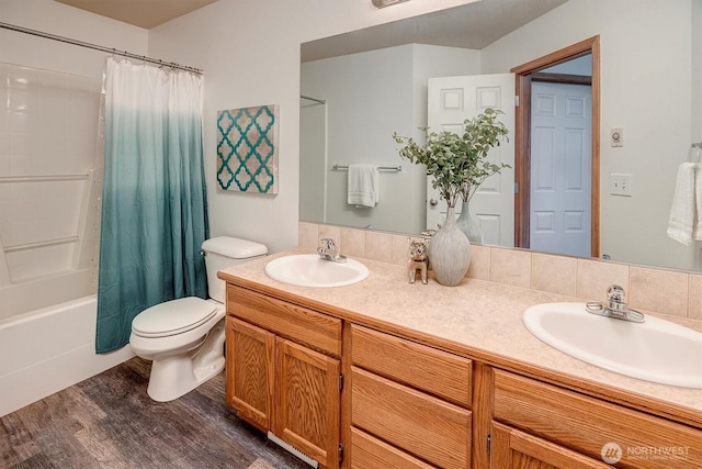 full bath with double vanity, a sink, toilet, and wood finished floors