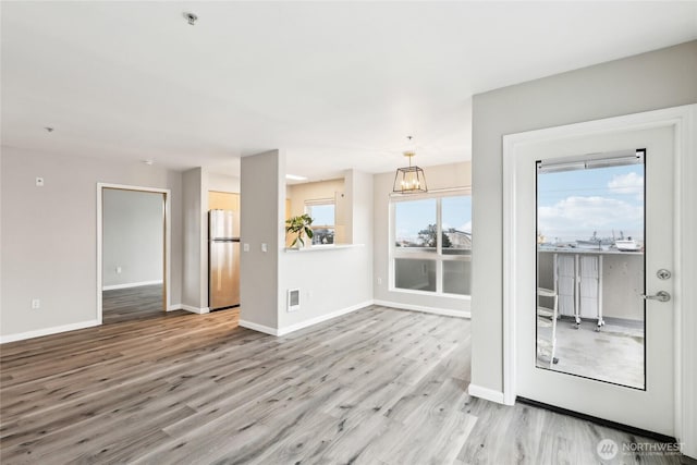 unfurnished room featuring a chandelier, wood finished floors, visible vents, and baseboards