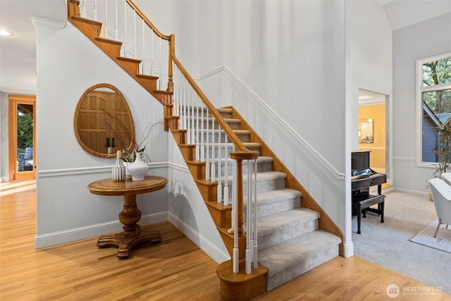 staircase with a high ceiling, baseboards, and wood finished floors