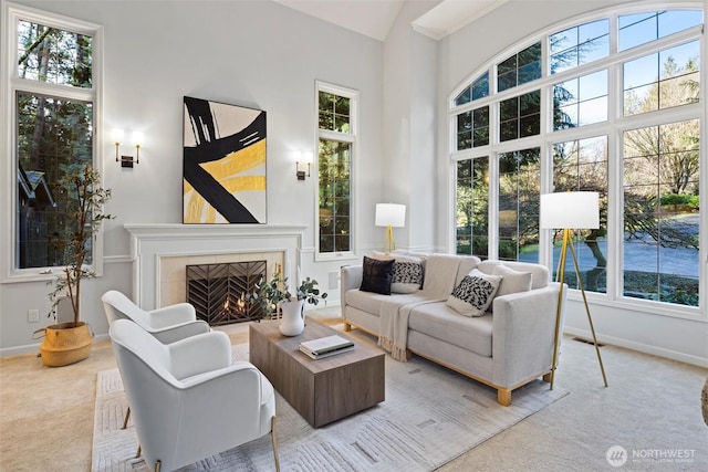 living room featuring plenty of natural light, carpet floors, a tiled fireplace, and high vaulted ceiling