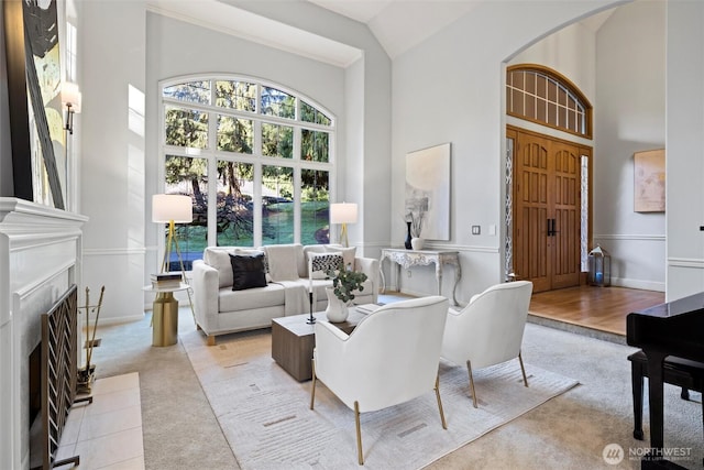 living area with high vaulted ceiling, arched walkways, a fireplace, and carpet floors