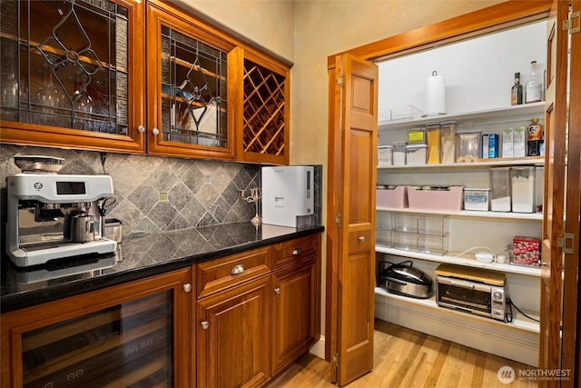 bar featuring light wood-type flooring, beverage cooler, a dry bar, and backsplash