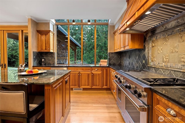 kitchen featuring range hood, brown cabinetry, crown molding, and high end stainless steel range