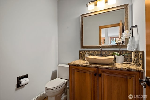 bathroom with backsplash, toilet, and vanity