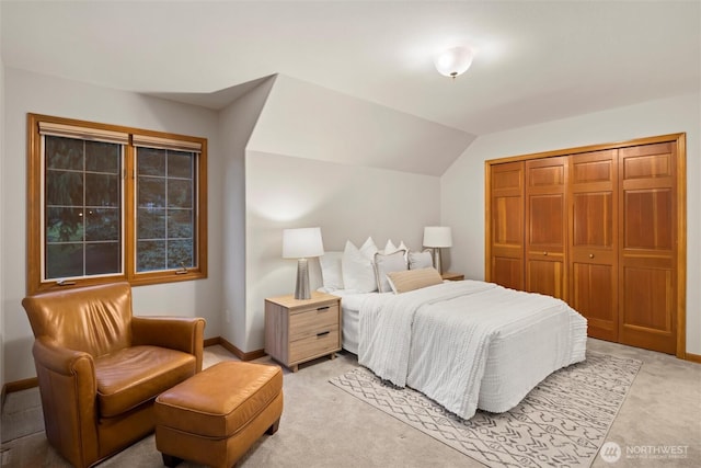 bedroom with light carpet, vaulted ceiling, a closet, and baseboards