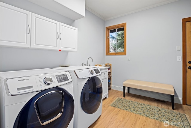 clothes washing area with light wood-type flooring, cabinet space, baseboards, and separate washer and dryer