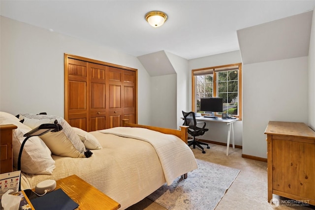 bedroom with a closet, light carpet, vaulted ceiling, and baseboards