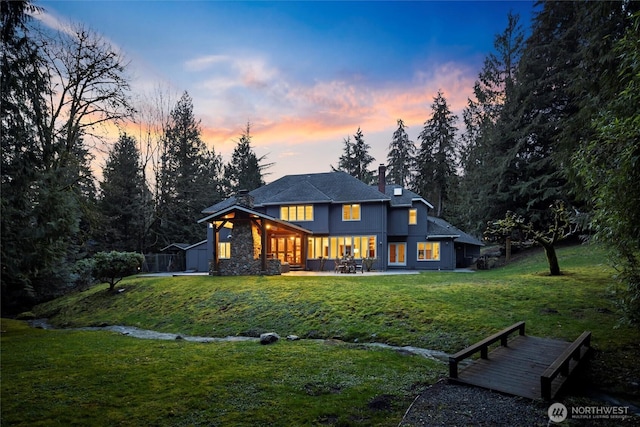 back of property with a patio area, a lawn, and a chimney