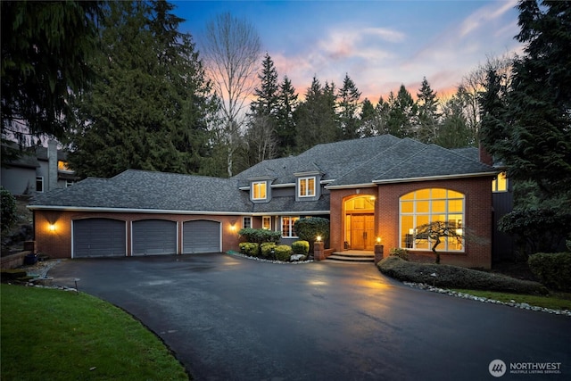 view of front of house featuring driveway, brick siding, an attached garage, and a shingled roof