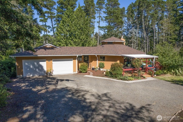 single story home with a garage, gravel driveway, and a shingled roof