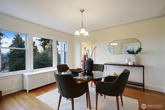 dining area with baseboards, radiator heating unit, light wood-type flooring, and an inviting chandelier