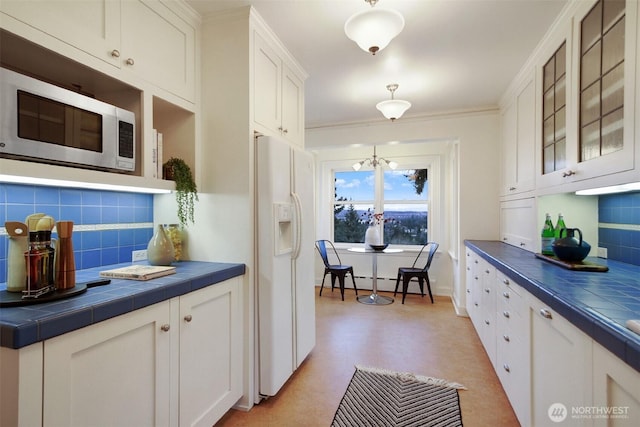 kitchen featuring white fridge with ice dispenser, glass insert cabinets, tile counters, and white cabinets