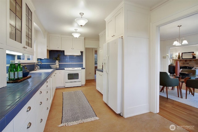 kitchen with glass insert cabinets, white appliances, white cabinetry, and decorative light fixtures