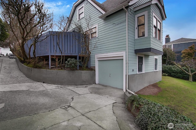 view of property exterior with a garage, a yard, driveway, and a wooden deck