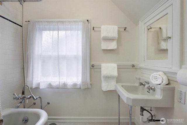 full bathroom with lofted ceiling, a bathing tub, and a healthy amount of sunlight