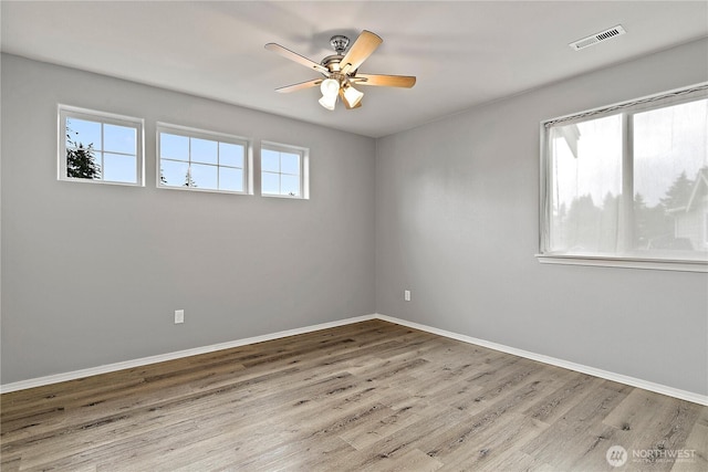 unfurnished room featuring a ceiling fan, visible vents, baseboards, and wood finished floors