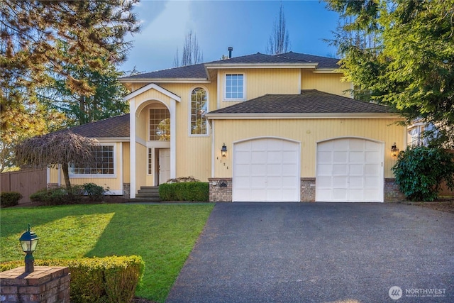 view of front of house with a front lawn, aphalt driveway, fence, an attached garage, and brick siding