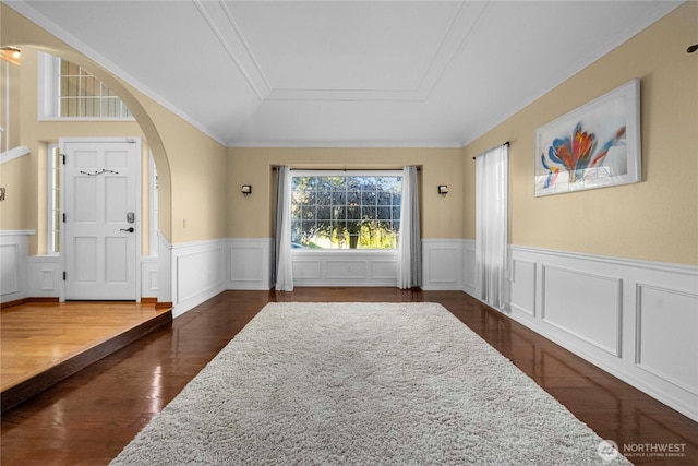 interior space featuring dark wood-style floors, arched walkways, and wainscoting