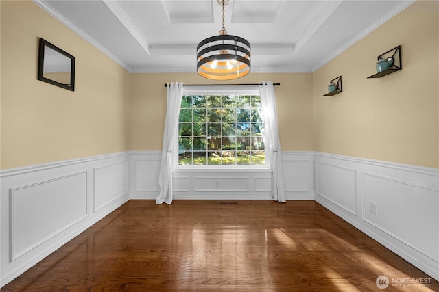 unfurnished dining area featuring a tray ceiling, a wainscoted wall, wood finished floors, and a chandelier