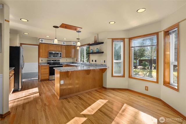 kitchen featuring brown cabinetry, appliances with stainless steel finishes, light wood-type flooring, and a peninsula