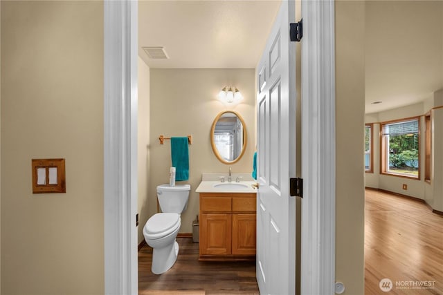 bathroom featuring vanity, wood finished floors, visible vents, baseboards, and toilet