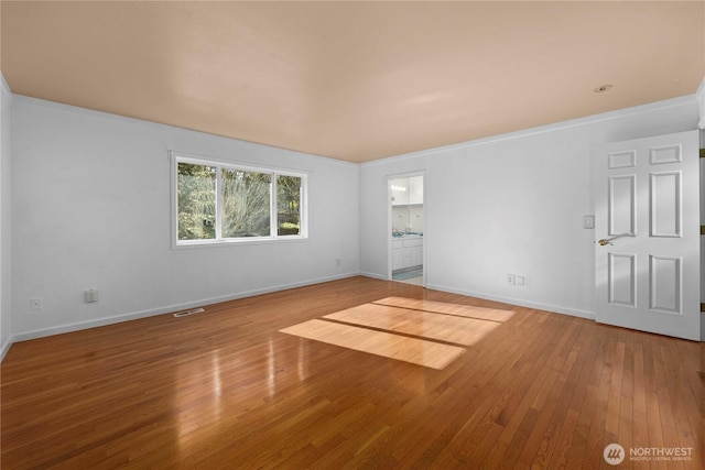 spare room featuring visible vents, baseboards, and hardwood / wood-style flooring