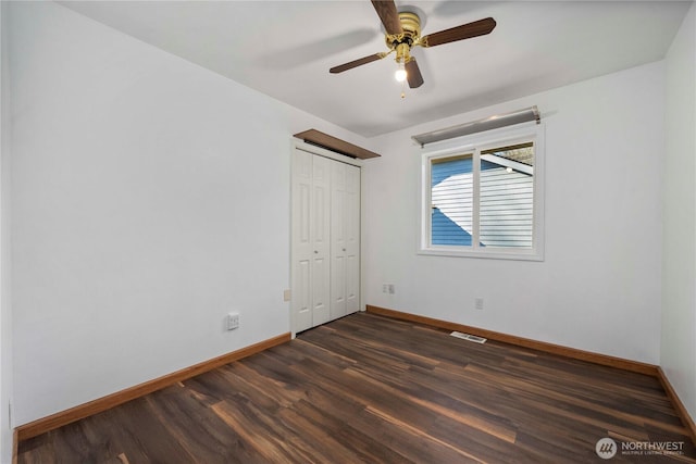 unfurnished bedroom with a closet, visible vents, dark wood-type flooring, and baseboards